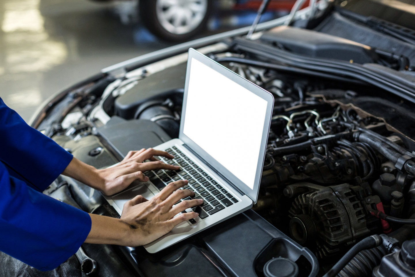 mechanic using laptop on car